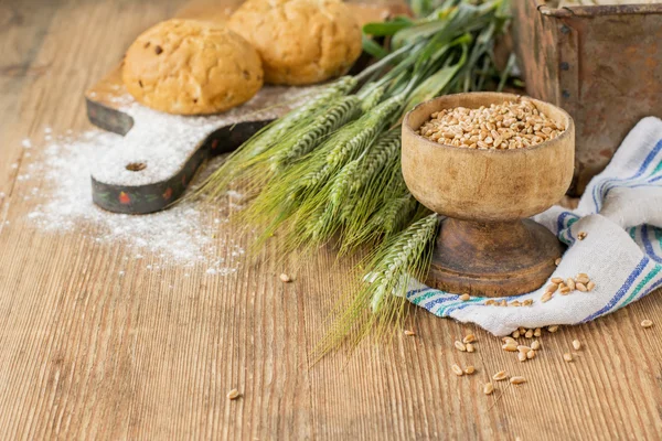 Ears of barley flour, bread on a wooden background — Stockfoto