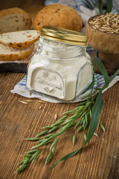 Oat flour, grain oats, oat bread on wooden background with home lyanm textiles — ストック写真