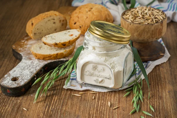 Oat flour, grain oats, oat bread on wooden background with home lyanm textiles — Stock fotografie