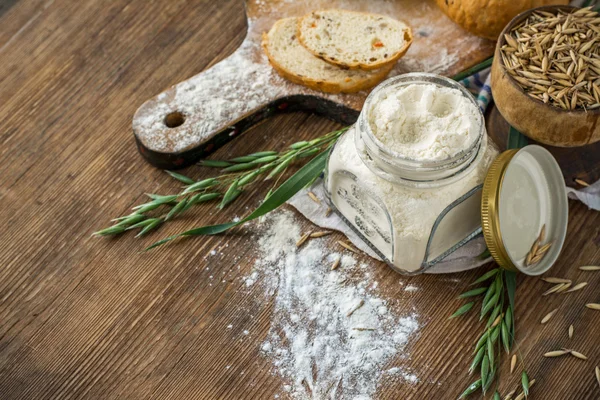 Oat flour, grain oats, oat bread on wooden background with home lyanm textiles — Stock fotografie