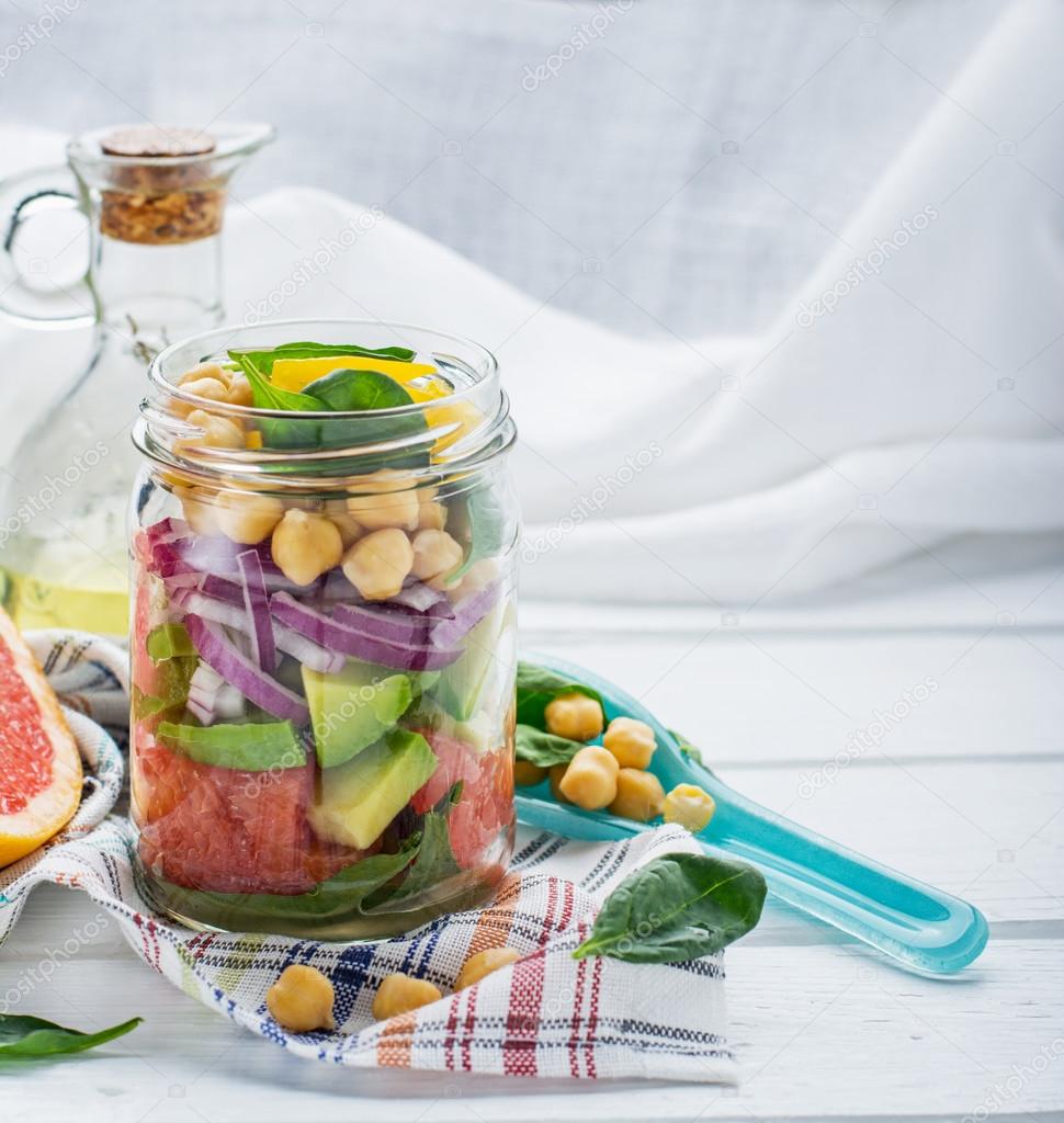 Fresh spring salad of grapefruit, avocado, sweet onion, spinach and chickpeas in a glass jar