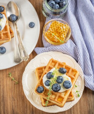 Homemade fresh crispy waffles for breakfast with blueberries and honey