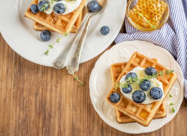 Homemade fresh crispy waffles for breakfast with blueberries and honey