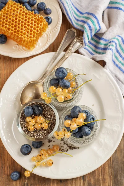 Milk pudding with chia seeds, blueberries and currants in a batch jars on wooden background — 스톡 사진