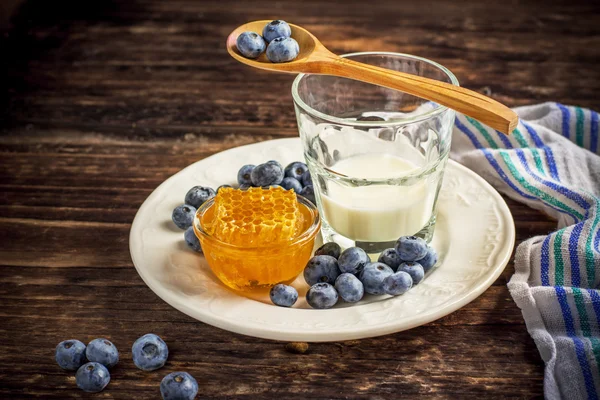 Jardinería de arándanos con un vaso de leche fresca y panales —  Fotos de Stock