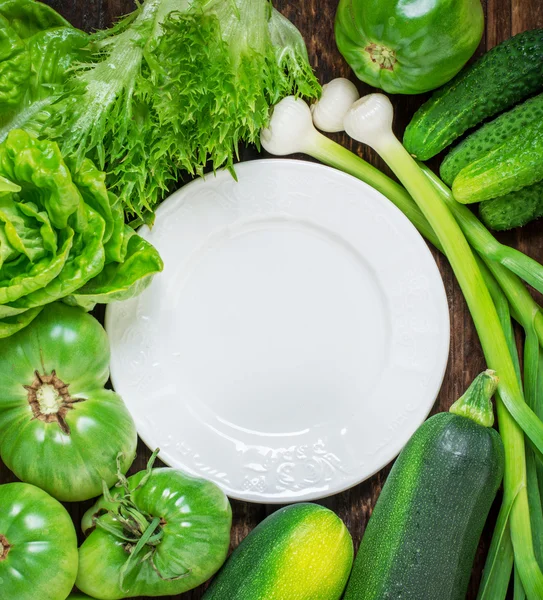 Placa de cerámica blanca rodeada de una variedad de verduras verdes — Foto de Stock