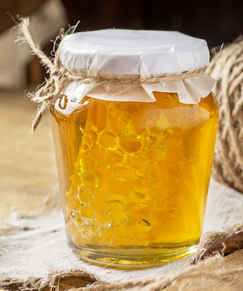 Mel floral fresco com favo de mel em um pequeno frasco de vidro — Fotografia de Stock
