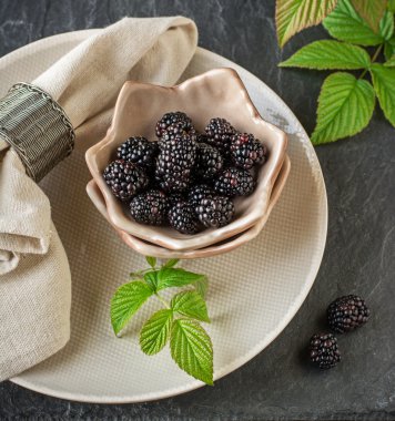 Seramik bardak el yapımı çanak çömlek içinde taze olgun böğürtlen kahvaltıda servis edilir