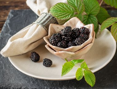 Seramik bardak el yapımı çanak çömlek içinde taze olgun böğürtlen kahvaltıda servis edilir