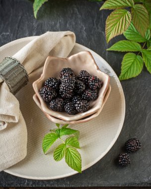 Seramik bardak el yapımı çanak çömlek içinde taze olgun böğürtlen kahvaltıda servis edilir