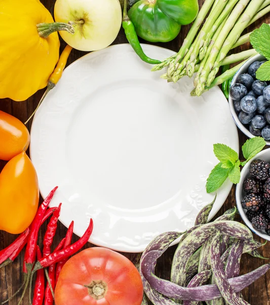 Frutas y verduras de todos los colores el arco iris sobre una mesa de madera sobre plato blanco — Foto de Stock