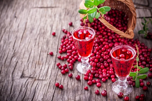 Zoete cranberry likeur in twee glazen op de achtergrond van rijp bessen — Stockfoto