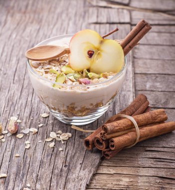 Yoğurt, tarçın ve bir cam kabın içinde elma dilim ile gece yulaf ezmesi