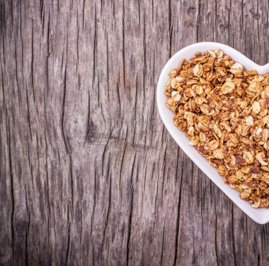 Home caramel granola in a white ceramic dish shape of heart