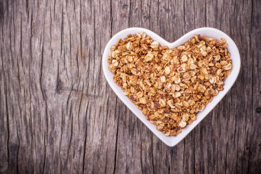 Home caramel granola in a white ceramic dish shape of heart