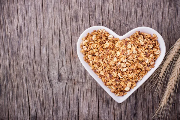 Home caramel granola in a white ceramic dish shape of heart — Stock Fotó