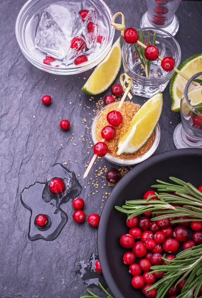 Ingredients for cranberry cocktail with lime and rosemary on a black stone — 스톡 사진