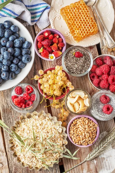 ingredients for a healthy breakfast - berries, fruit and muesli on wooden table, close-up