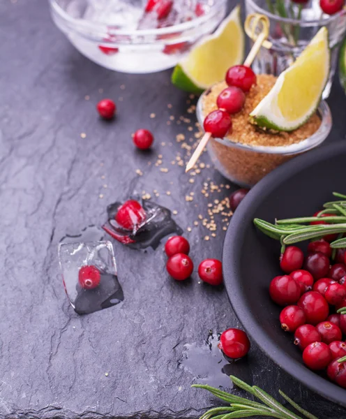 Ingredients for cranberry cocktail with lime and rosemary on a black stone — ストック写真