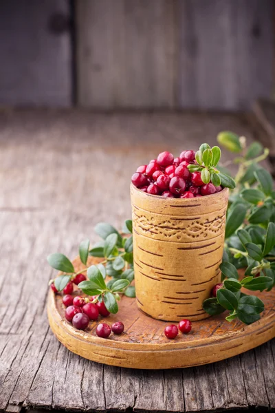 Fresh forest berries and lingonberry twigs in cup of birch bark on a wooden background. — Stockfoto