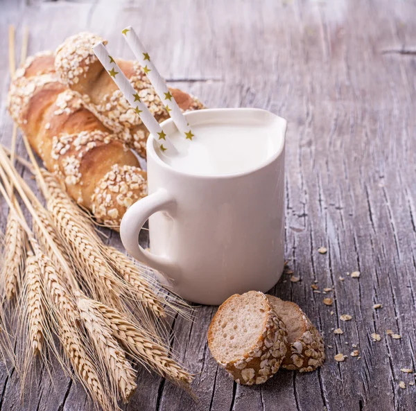 Jarro com leite para café da manhã e pão caseiro fresco baguetes orelhas — Fotografia de Stock
