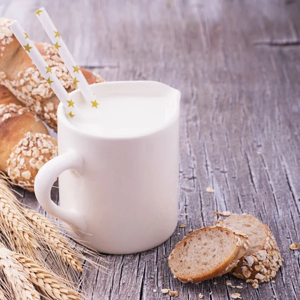 Jarro com leite para café da manhã e pão caseiro fresco baguetes orelhas — Fotografia de Stock