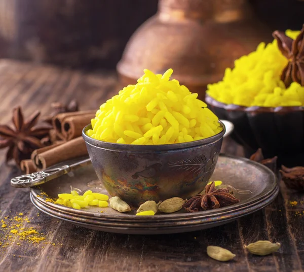 Bright yellow boiled rice with turmeric and aromatic spices on a dark wooden background in old vintage metal bowl — Stock Photo, Image