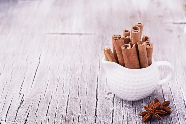 Cinnamon sticks and anise stars on a simple light wooden background