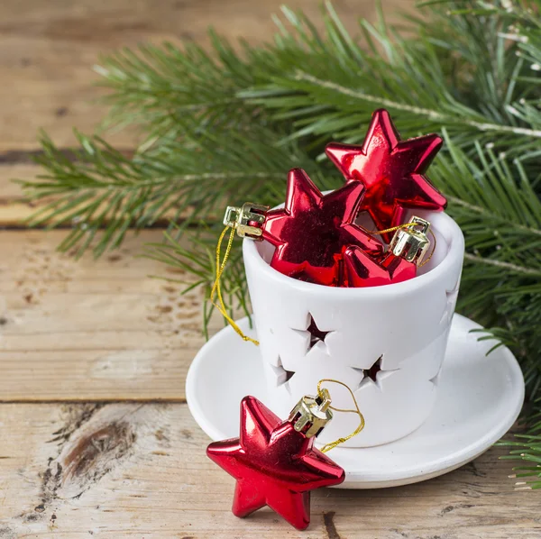 Noel oyuncaklar kırmızı yıldız çam dalları basit bir ahşap zemin üzerine beyaz şamdan — Stok fotoğraf