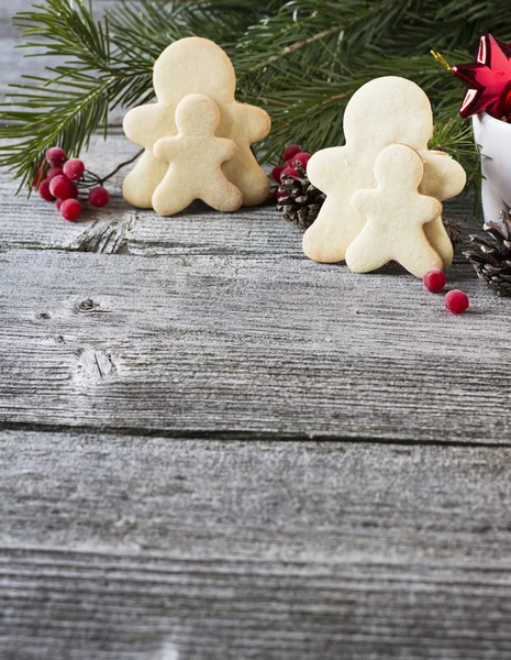 Hembakade pepparkakor män på en enkel trä bakgrund med fir grenar — Stockfoto