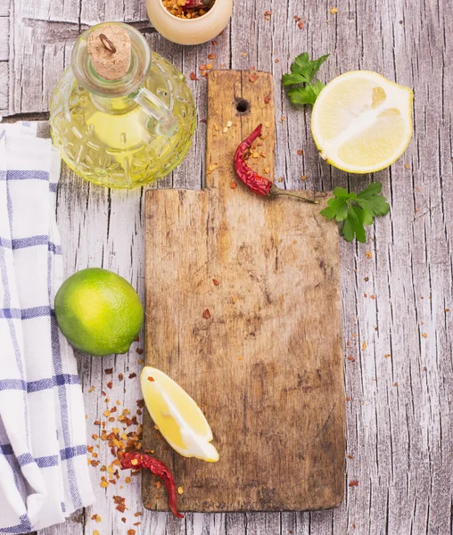 Tabla de cortar vieja con un chile seco rojo picante, limón y lima —  Fotos de Stock