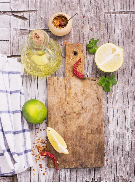 Old cutting board with a spicy red dried chilli, lemon and lime