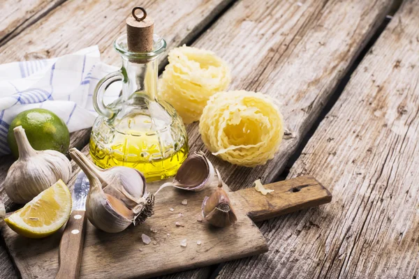 Kitchen simple still life of pasta, olive oil, fresh garlic, herbs and grasses — Stock fotografie