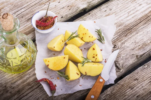 Rauwe aardappelen en mes op een houten achtergrond — Stockfoto