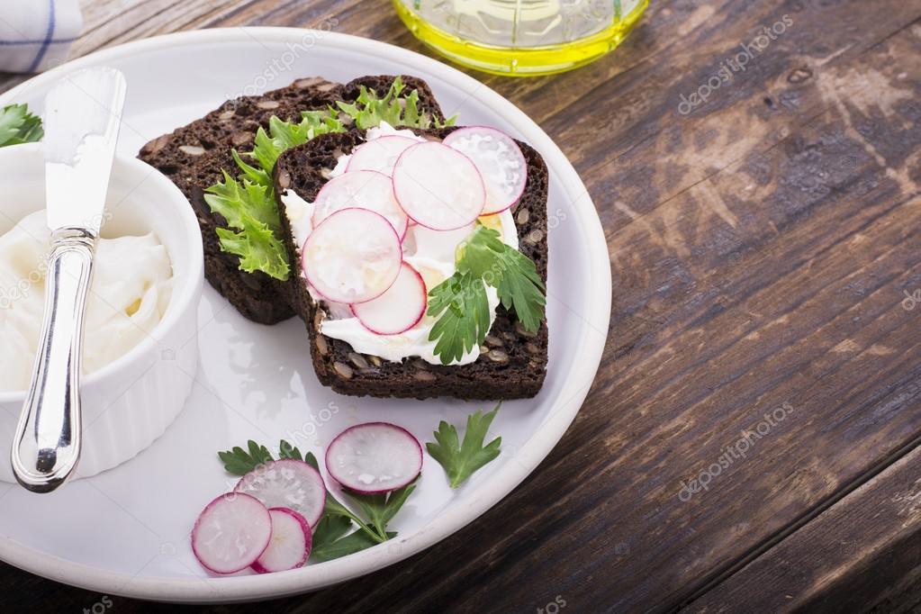 Healthy sandwiches for breakfast or snack dark grain bread with curd cream cheese, radish, herbs