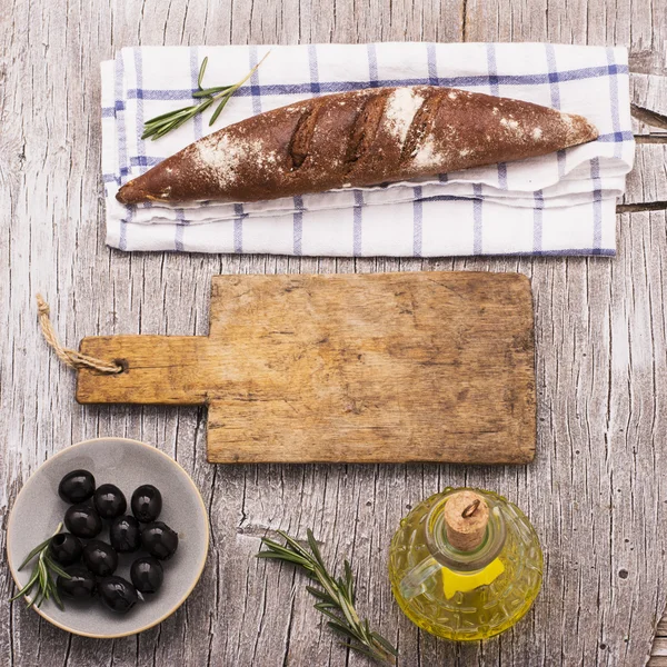 Eenvoudige keuken-stilleven van vers donker-korrel brood, een kruik olijfolie — Stockfoto