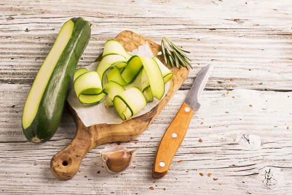 Thin slices of zucchini on olive board — Stock Photo, Image