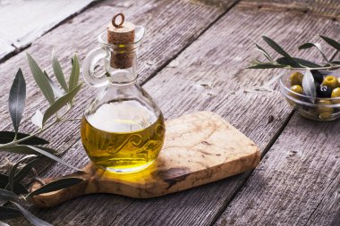Dalları tarafından çevrili kesme tahtası üzerinde sızma zeytinyağı ile sürahi
