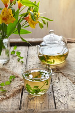 Melissa tea in cup, teapot with fresh leaves and flowers