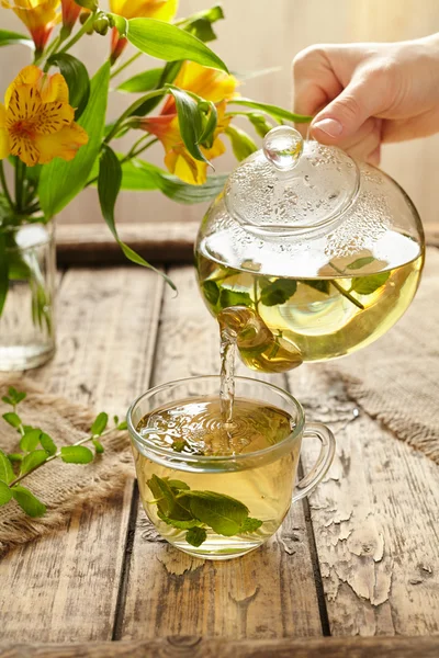 Sage tea pouring in glass transparent cup from teapot — Stock Photo, Image