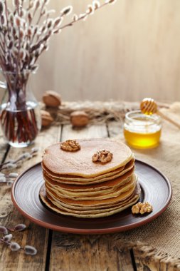 Stack of pancakes with nuts on vintage wooden table