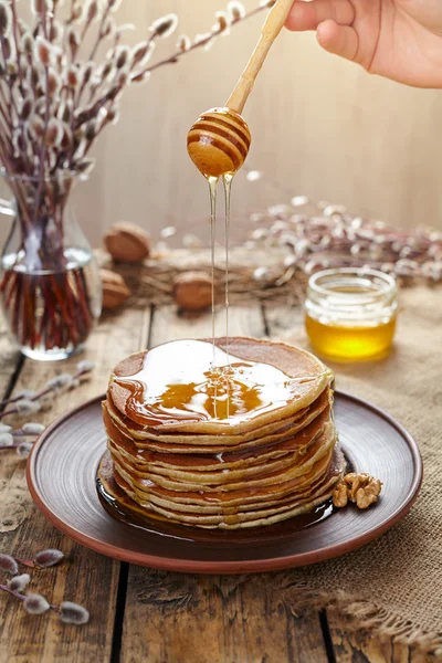 Fließender Honig auf einem Stapel hausgemachter traditioneller Pfannkuchen mit Nüssen — Stockfoto