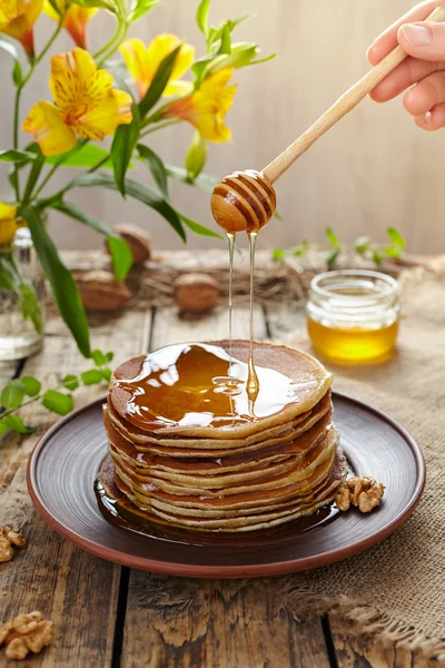 Fließender Honig auf einem Stapel traditioneller amerikanischer Pfannkuchen mit Blumen — Stockfoto