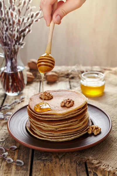 Fließender Honig auf einem Stapel Pfannkuchen mit Nüssen — Stockfoto