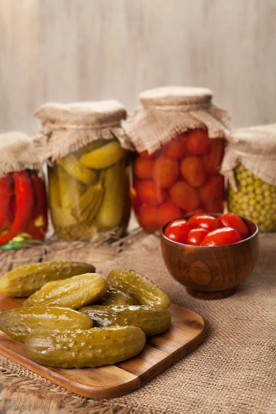 Pickled preserved vegetables in jars, cucumbers, pepper, tomatoes and peas — Stock Photo, Image