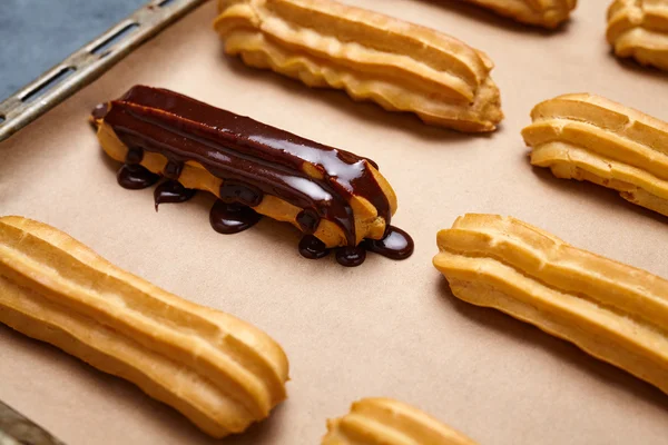 Eclairs con chocolate y crema batida preparándose en bandeja para hornear — Foto de Stock