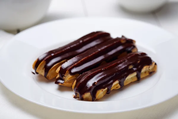 Eclairs ou profiteroles com cobertura de chocolate em prato branco — Fotografia de Stock