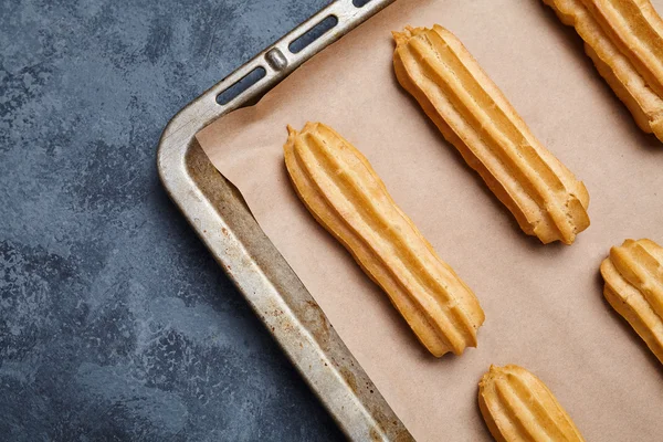 Eclairs tradicional pastelería francesa en bandeja para hornear con marco vacío — Foto de Stock