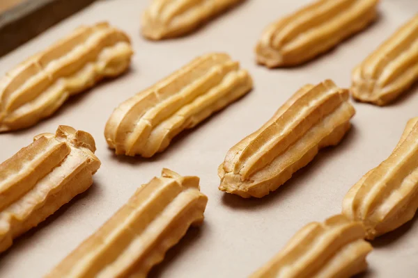 Homemade eclairs or profiterole dessert food on baking sheet — Stock Photo, Image