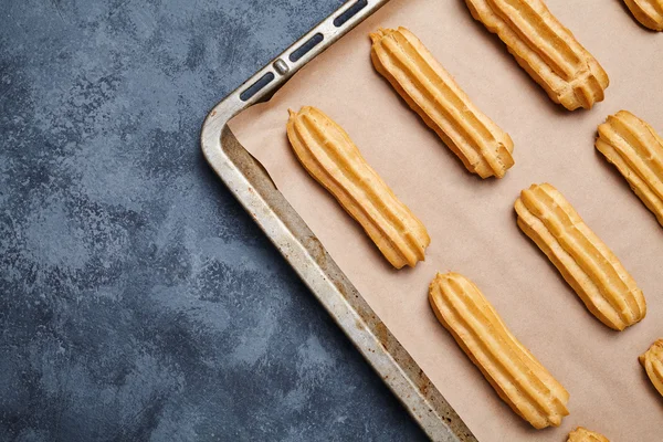 Eclairs postre francés tradicional en bandeja para hornear con marco vacío — Foto de Stock